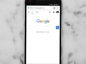 black Android smartphone showing google site on white surface