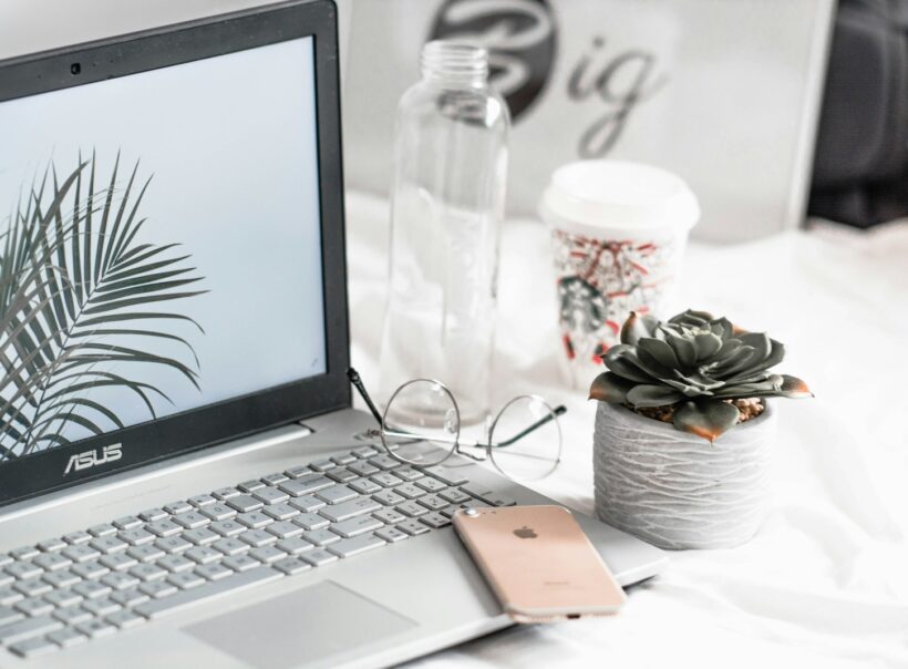 turned-on Asus laptop near eyeglasses, succulent plant, and empty clear glass bottle